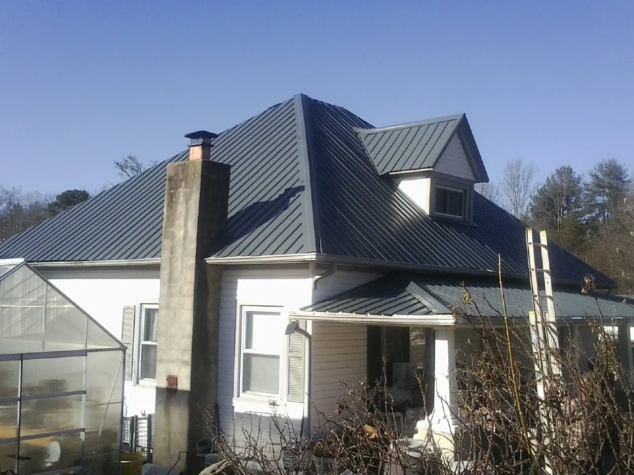 Dark blue standing seam metal roof on a white farmhouse with dormer — Slate & Tile Roof Repair by Roofing Brothers in New Market