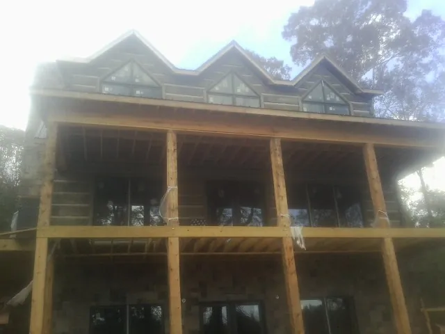 Dormers and porch framing on a large log home under construction — Roof Coating work by our crew in New Market