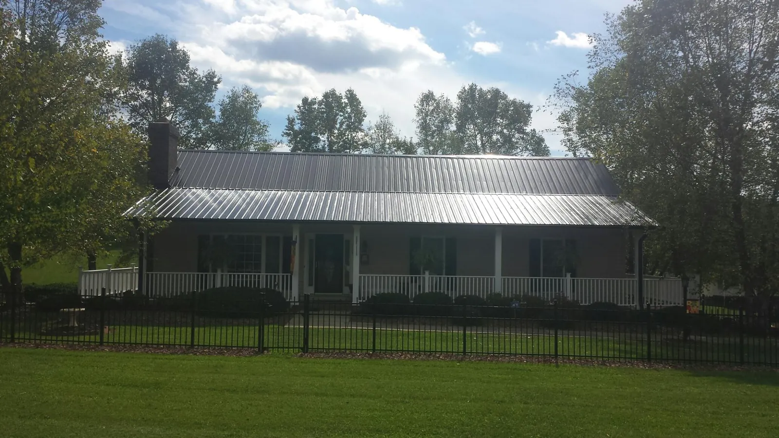 Gray metal roof on a brick ranch with a full width front porch — Gutter Guard Installation work by our crew in New Market
